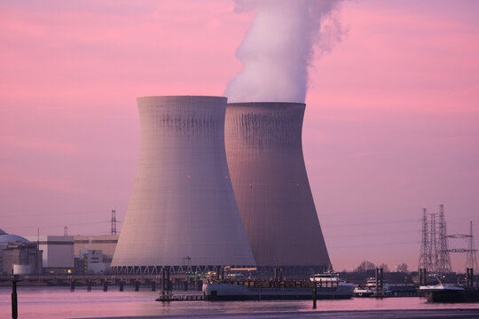 Nuclear power plant with cooling towers releasing steam. Thermal energy production and industrial electricity generation facility.