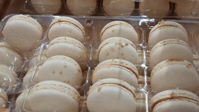 Rows of delicate cream macarons arranged in a pastry display, elegant dessert, colorful confectionery, gourmet baking, sweet celebration.