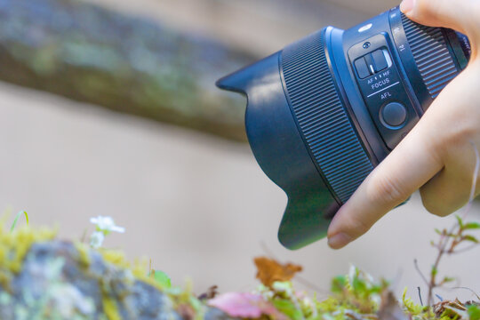 Gros plan d&rsquo;une main tenant un objectif photographique moderne en plein air