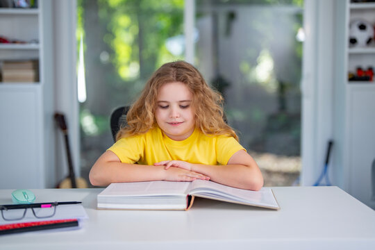 Clever child reading a book at home. Kid read book in a home interior. Smart reader enjoying a story books at home. Clever kid reading book and learning in the playroom. Child holding a book.