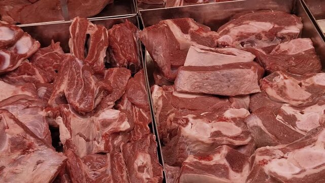 Fresh cuts of raw meat arranged in a supermarket display, butcher counter, food retail, protein ingredients, and culinary preparation.