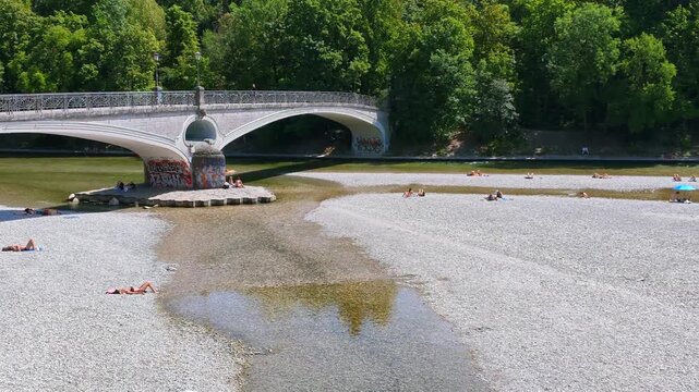 Menschen erfrischen sich am Ufer der k&uuml;hlen Isar an einem hei&szlig;en Sommertag, M&uuml;nchen, Oberbayern, Bayern, Deutschland