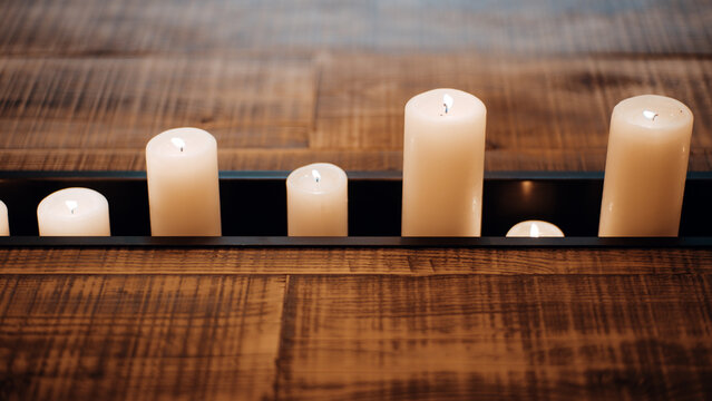 Distinctive reclaimed wood table features a recessed black metal trough filled with glowing white pillar candles, showcasing warm rustic interior design
