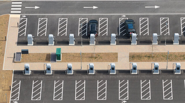 Aerial view of an electric vehicle charging station in a parking lot with two cars parked at charging points in Winchester, England, United Kingdom.