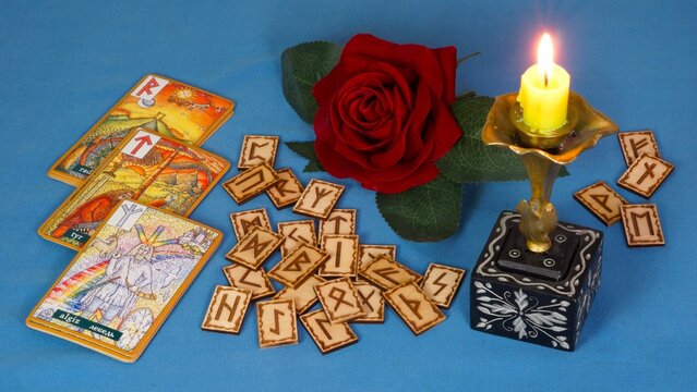Rune divination against a backdrop of a candle and a rose flowe