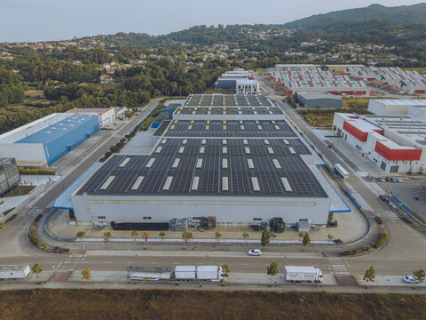 Aerial view of the Porto do Molle industrial park featuring a large warehouse with solar panels on its roof surrounded by other industrial facilities and roads in Nigran, Pontevedra, Spain.