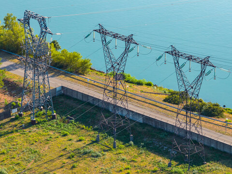 Aerial view of high voltage transmission towers and power lines near a river in Saulce-sur-Rhone, Auvergne-Rhone-Alpes, France.