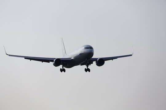 A commercial passenger airplane flies in the sky before landing.