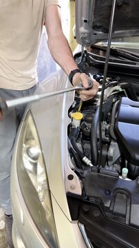 Male mechanic using a ratchet wrench to tighten bolts on a car engine in a garage, showcasing detailed work on automotive components and tools