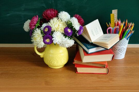 school stationery, flowers in vase and learning books on table against chalkboard. symbol of beginning of the school year, teacher's day, Knowledge Day. education, back to school,1 September concept