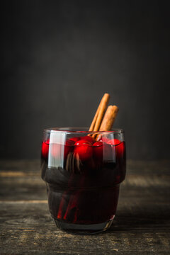 Mulled wine with orange, cranberry and cinnamon on rustic wooden background. Selective focus.