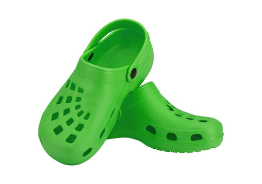 Pair of bright green clogs with strap on checkered background.