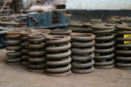 Stack of Heavy Duty Metal Coil Springs for Railway Suspension in Factory Workshop