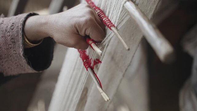 Indigenous Kalash Woman weaves a traditional Pakistan Carpet of Multicolored wool. Weaving and making handmade carpets.