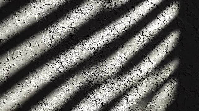 Changing sunlight and window shadows move across a rough plaster wall, creating an abstract monochrome background with shifting light and texture