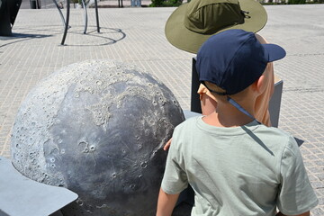 Young Boys Studying the Moon and Its Craters on a Small Model
