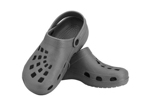 Pair of grey clogs with strap on checkered background.
