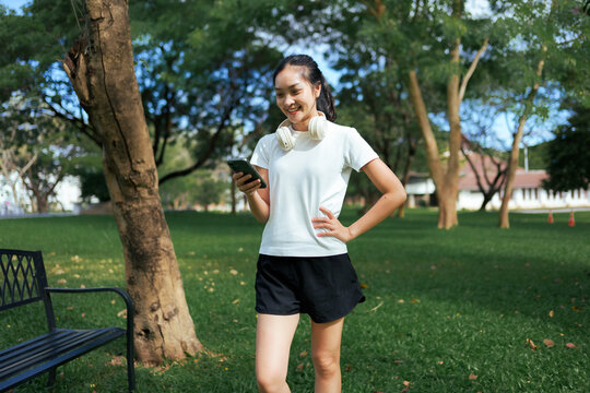 Young woman smiling using smartphone outdoors in park