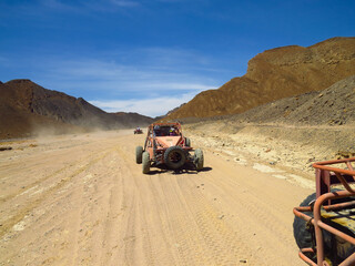 Off-Road Buggy Convoy Driving Through Desert Mountains © Tony