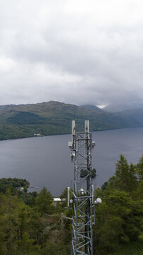 Aerial view of a telecommunications tower situated amidst lush forest overlooking the expansive waters of Loch Sloy in Argyll and Bute Council, Scotland, United Kingdom.