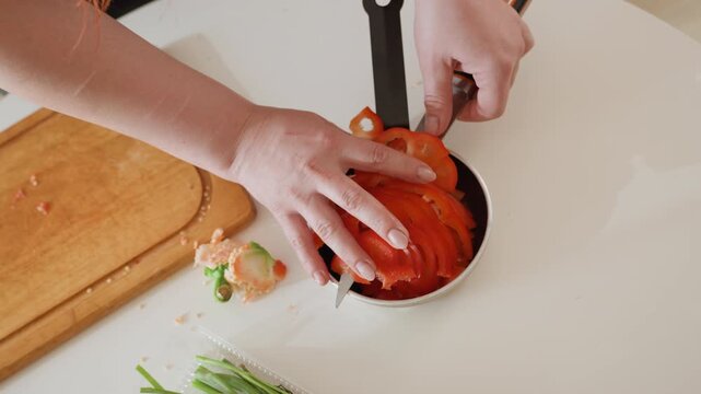 Top-down sequence showing hands slicing and arranging fresh tomato slices into small frying pan beside wooden cutting board and knife; visible finger movement presses layered tomato rounds into pan