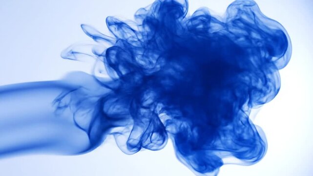 Blue ink diffusing in water creating abstract clouds against white background