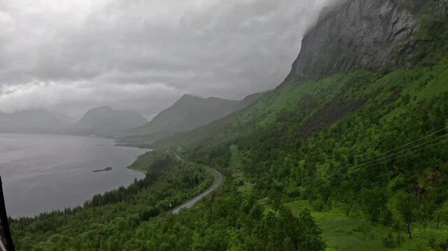 High angle static ultra wide view of winding coastal road and green mountains in Bergsbotn Senja Norway