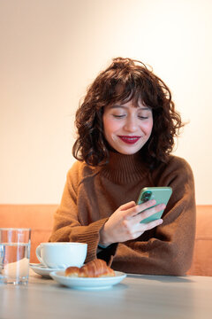 Smiling woman using smartphone at cafe