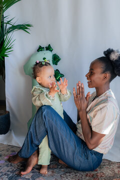 Woman playing with child near balloon at first birthday celebration