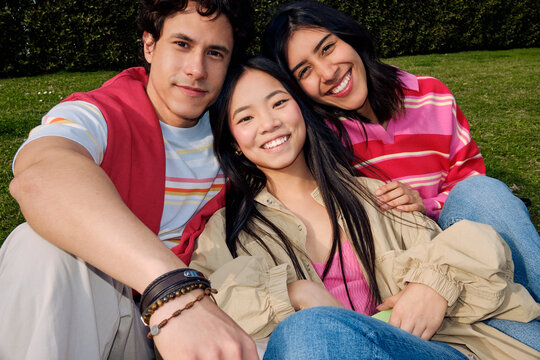 Three Friends Sitting Together on Grass