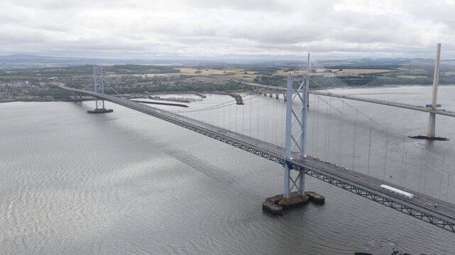 Aerial view of the Forth Road Bridge spanning the Firth of Forth with traffic under a cloudy sky in South Queensferry, United Kingdom.