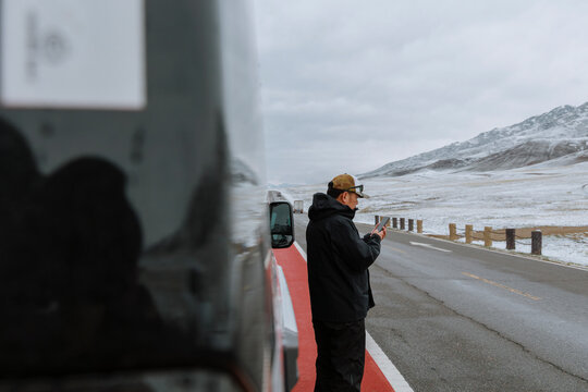 Self-Driving Traveler Checking Routes by a Snowy Highway.