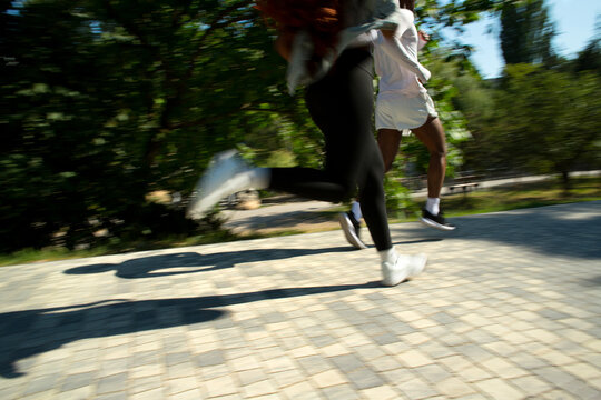 Black runners man and woman blurred into motion at summer street.