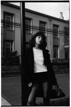 Young woman leaning on street pole