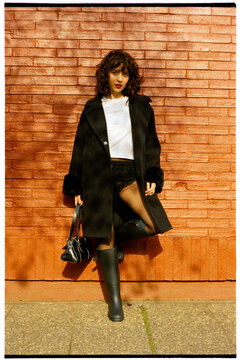 Young woman leaning on brick wall