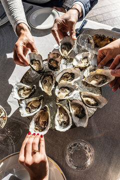 Friends sharing a large platter of fresh raw oysters at a restaurant