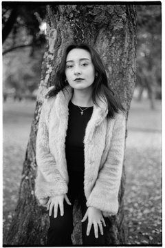 Posing young woman at tree trunk