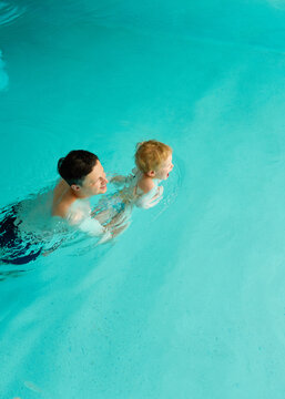 Man Swims With Toddler in Pool During Sunny Day