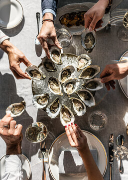 Friends sharing a large platter of fresh raw oysters at a restaurant