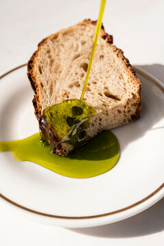 Pouring vibrant green olive oil onto a slice of sourdough bread
