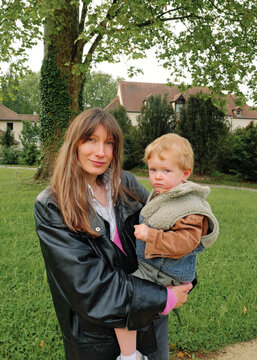 Mother holding her toddler son, looking at the camera. 