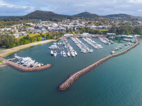 Rows of boats behind a rock breakwater alongside a coastal town
