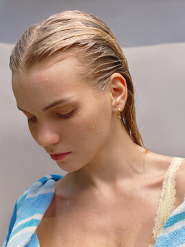 Young Woman With Wet Hair Looks Down While Wearing a Towel