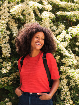 Happy Curly Haired Woman Laughing Outdoors With Backpack 
