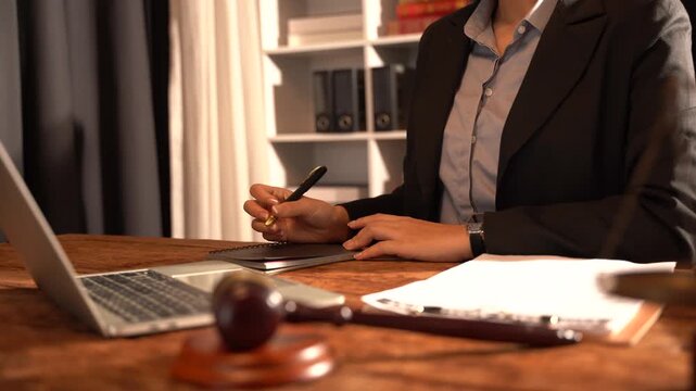 Lawyer Working in Office: A lawyer in a sharp suit meticulously reviews documents and types on a laptop in a well-organized office, conveying professionalism and dedication.