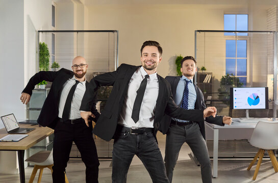 Businessmen team dance in office celebration. Happy colleagues and coworkers move with energy, cheering success after a winning project in a modern workspace. Clear concept of team victory.