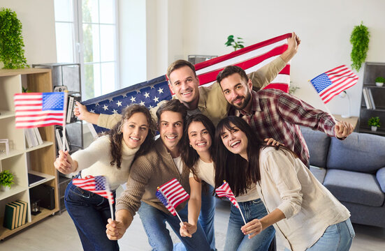 Happy USA people group waving flag together. Friends pose with the American banner, waving mini flags for independence celebration and sharing joy. Patriotic unity and joyful friendship.