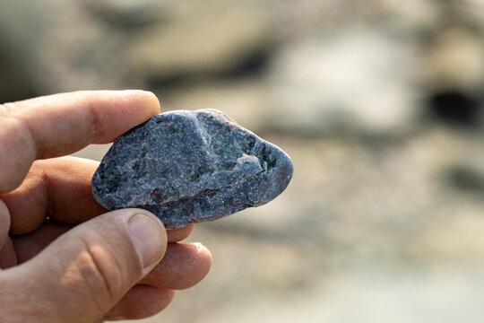 Quebec, Canada, 28 July 2026 : A person's hand holds a small, dark, irregular stone.