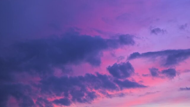 Morning or evening sky. Colorful clouds fill twilight with gradients of purple and pink during sunset or sunrise. Natural background. Beauty in nature. Expressive cloudscape. High quality 4K footage.