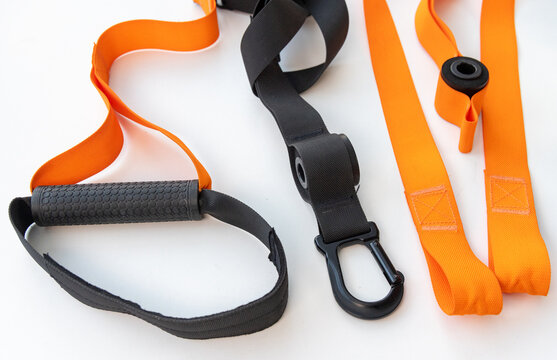 Closeup of black and orange fitness suspension training straps on white